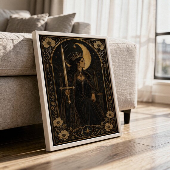 Gothic moon queen wall art print in a white frame leaning against a gray sofa on a sunlit wooden floor.
