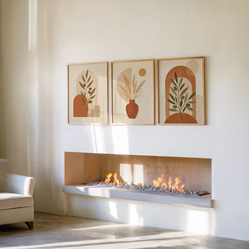 Set of 3 framed boho plant art posters hanging on the wall above a modern fireplace.