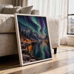 Aurora borealis mountain landscape wall art print in a white frame leaning against a gray sofa on a sunlit wooden floor.
