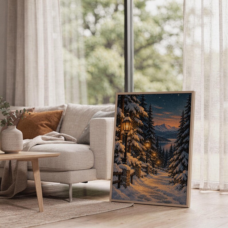 Snowy forest path wall art print leaning on the floor beside a cream armchair next to large garden windows.