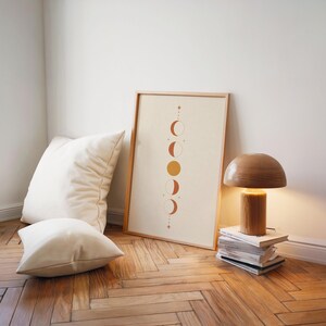 Minimalist celestial poster set on floor beside modern table lamp and cushions