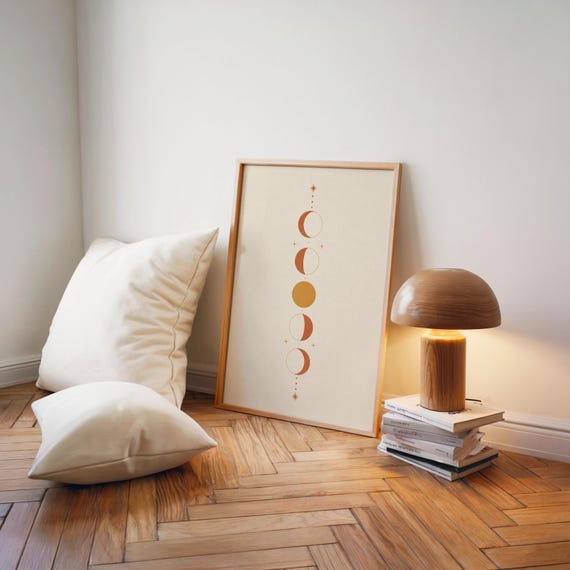 Minimalist celestial poster set on floor beside modern table lamp and cushions