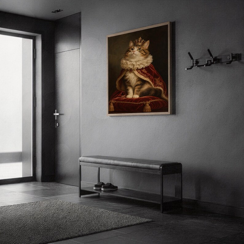 Royal cat portrait wall art print in a silver frame leaning against a sofa beside a decorative marble sphere.