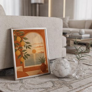 Mediterranean lemon and sea view arch print in a silver frame leaning against a sofa beside a decorative marble sphere.