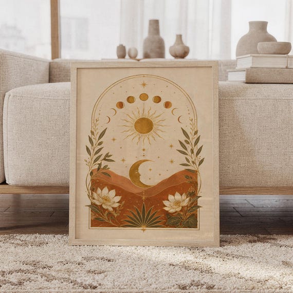 Celestial sun and moon wall art print featuring warm gold, terracotta, cream, and olive tones, moon phases, a radiant sun, crescent moon, stars, mountains, and botanical flowers in a vintage boho style, framed and leaning against a beige sofa on a textured rug in a bright Scandinavian living room.