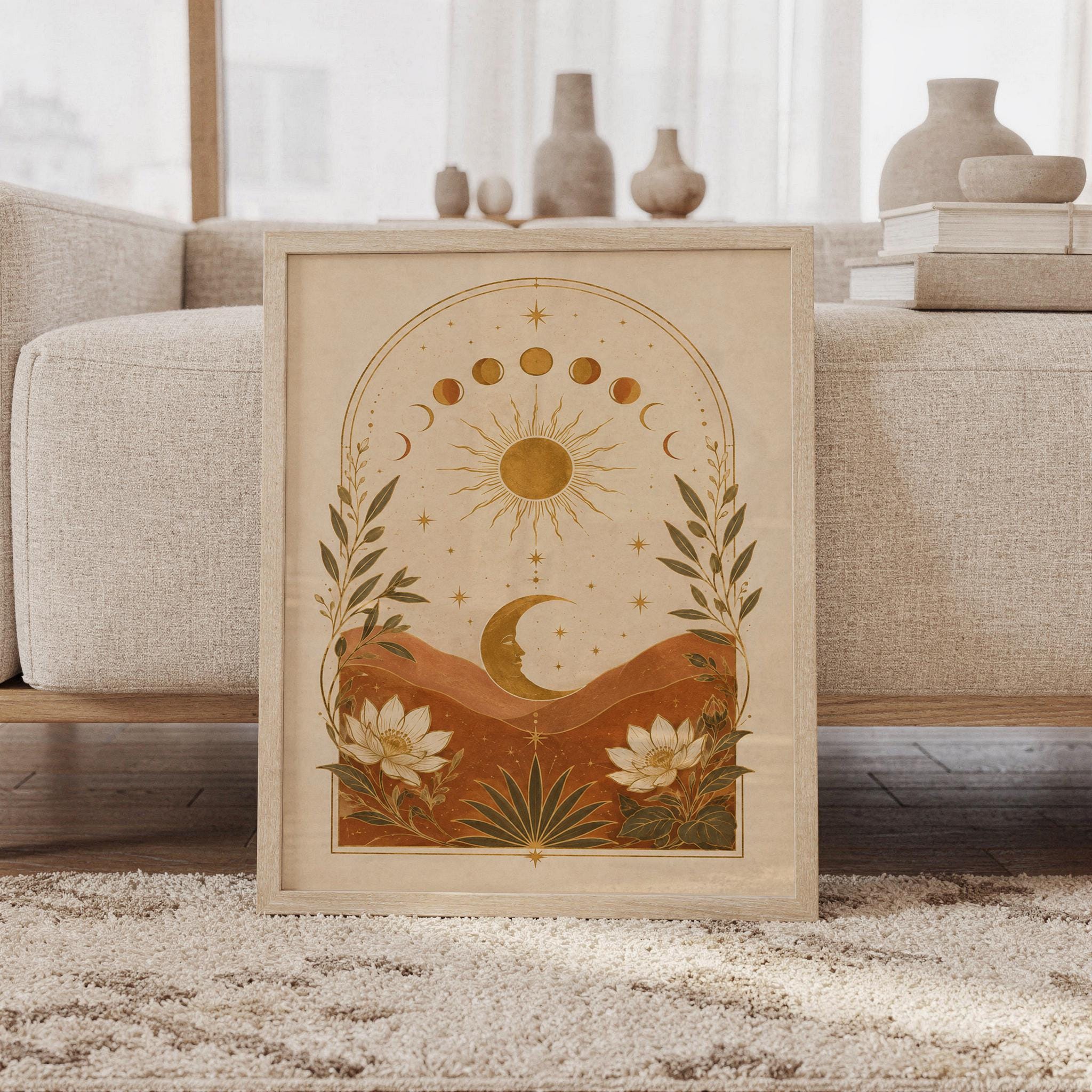 Celestial sun and moon wall art print featuring warm gold, terracotta, cream, and olive tones, moon phases, a radiant sun, crescent moon, stars, mountains, and botanical flowers in a vintage boho style, framed and leaning against a beige sofa on a textured rug in a bright Scandinavian living room.