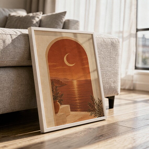 Mediterranean crescent moon arch print in a white frame leaning against a gray sofa on a sunlit wooden floor.