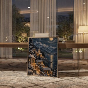 Snowy mountain village wall art print standing on a wooden desk in a home office in warm evening light.