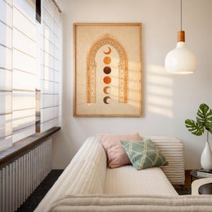 Framed moon phase tapestry style art poster hanging above a white sofa in a sunlit modern bohemian living room⁠