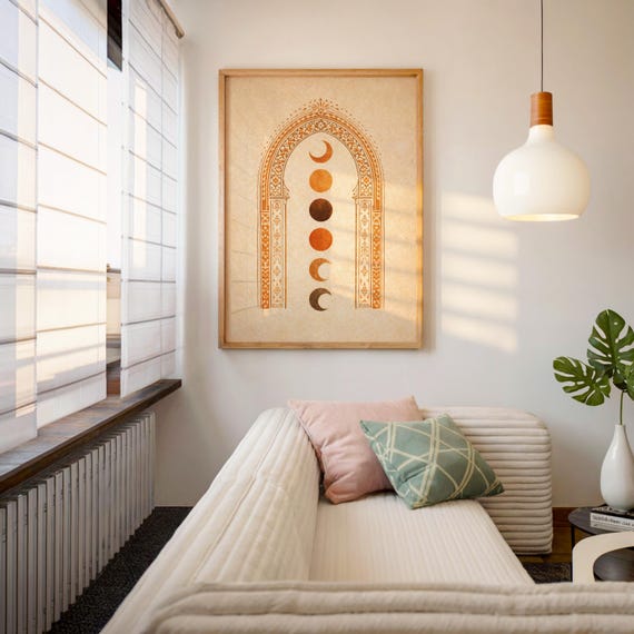Framed moon phase tapestry style art poster hanging above a white sofa in a sunlit modern bohemian living room⁠