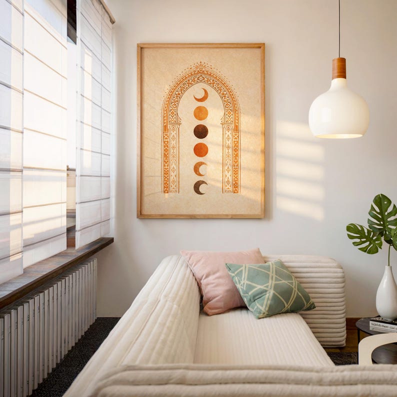 Framed moon phase tapestry style art poster hanging above a white sofa in a sunlit modern bohemian living room⁠