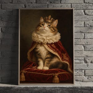 Royal cat portrait wall art print featuring a tabby cat in a jeweled gold crown, ivory lace ruff, and richly embroidered burgundy velvet robe, framed and leaning against a beige sofa on a textured rug in a bright Scandinavian living room.