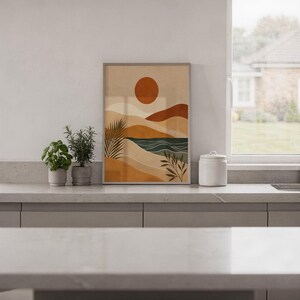 Muted modern abstract landscape art framed on kitchen wall above wooden cabinets in home.