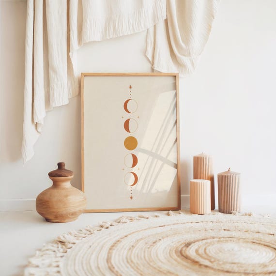 Terracotta celestial wall art print resting on floor with woven boho rug