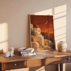 Mediterranean moonlit coastal wall art print hanging above a bed with sage green pillows in a calm neutral bedroom.