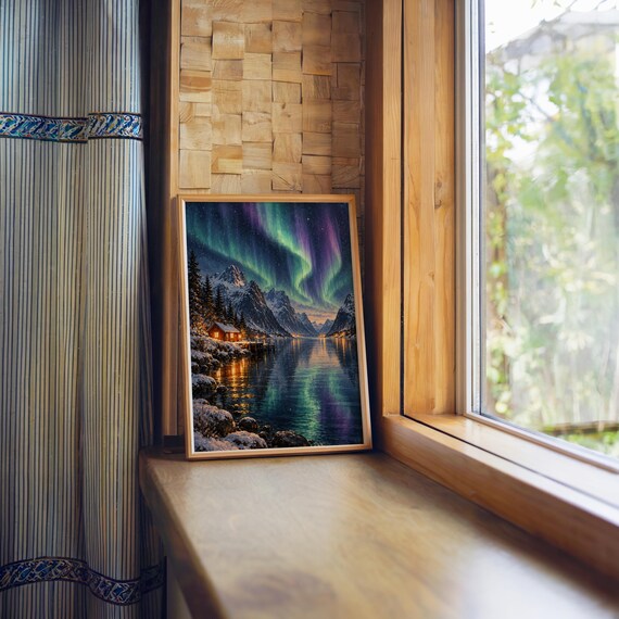 Aurora borealis mountain landscape wall art print standing on a wooden window sill in warm natural light.