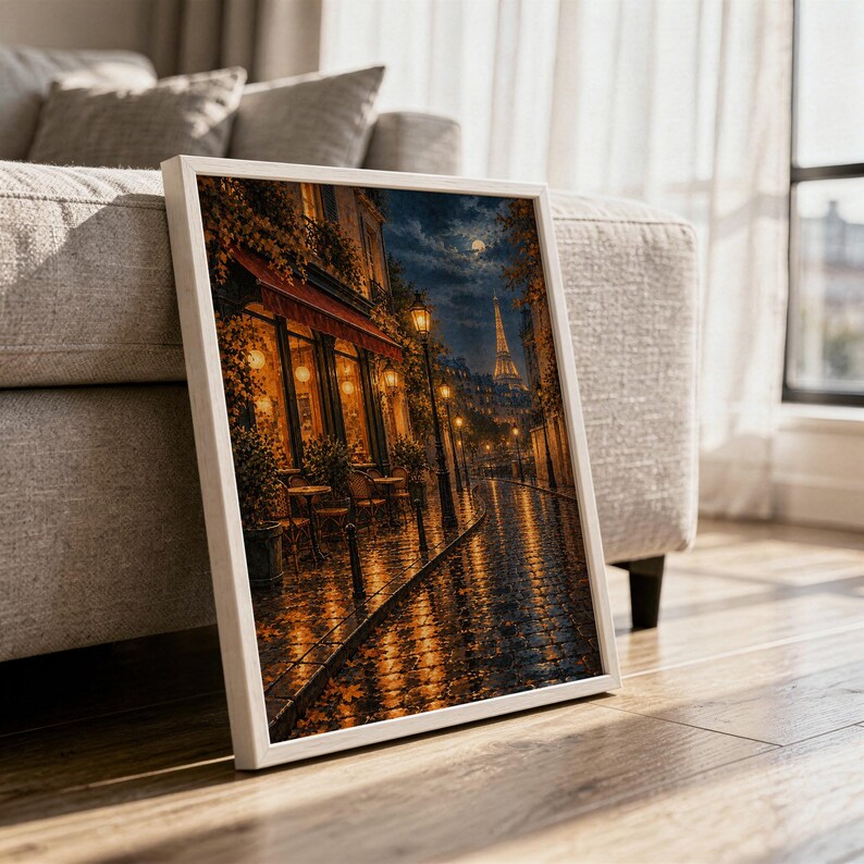 Paris eiffel tower wall art print in a white frame leaning against a gray sofa on a sunlit wooden floor.