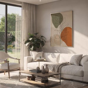 Framed minimalist leaf line art hanging above a sofa in a bright modern living room.