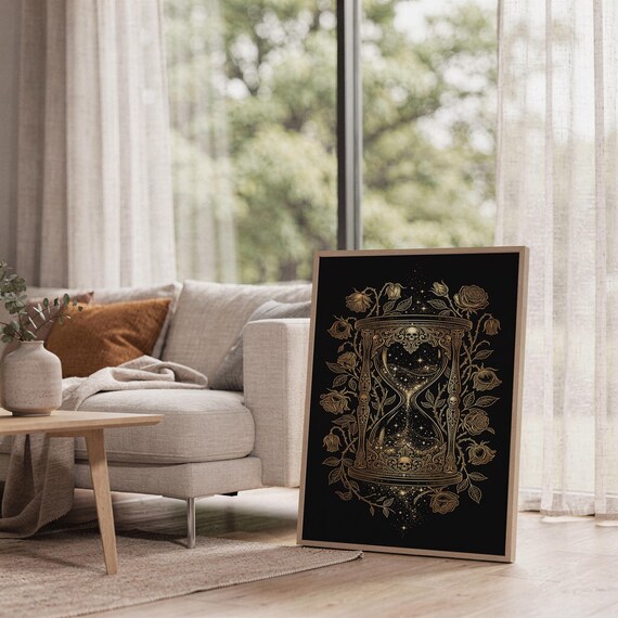Gothic hourglass wall art print leaning on the floor beside a cream armchair next to large garden windows.