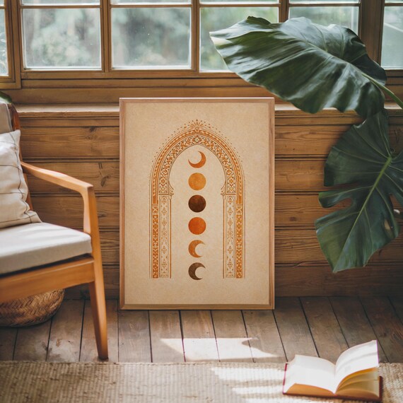 Minimalist bohemian moon phase art print in a natural wood frame styled next to an armchair and window light