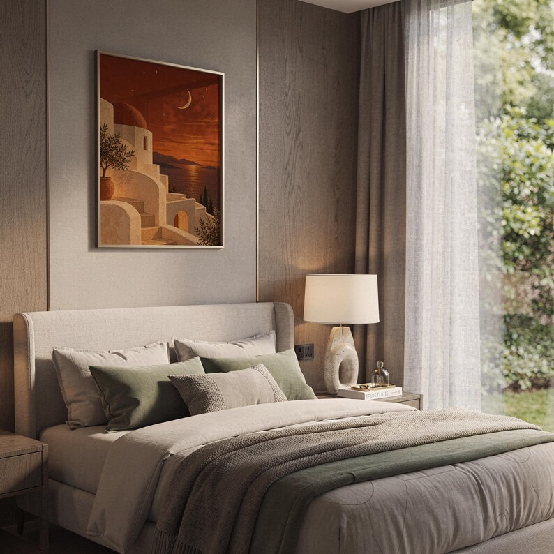 Mediterranean moonlit coastal wall art print leaning on a wooden desk against a warm beige wall in soft window sunlight.