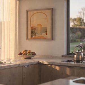 Mediterranean sunset arch print standing on a wooden desk in a home office in warm evening light.