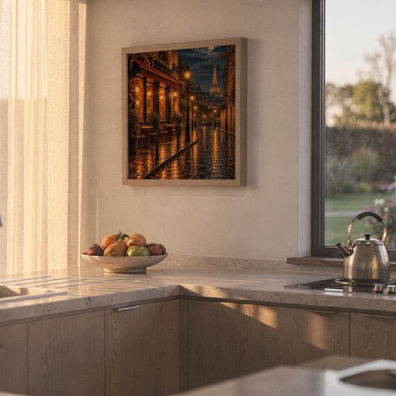 Paris eiffel tower wall art print hanging above a stone countertop with a fruit bowl in a sunny kitchen.