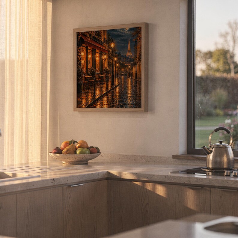 Paris eiffel tower wall art print hanging above a stone countertop with a fruit bowl in a sunny kitchen.
