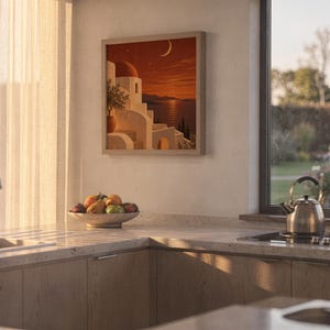 Mediterranean moonlit coastal wall art print hanging above a stone countertop with a fruit bowl in a sunny kitchen.