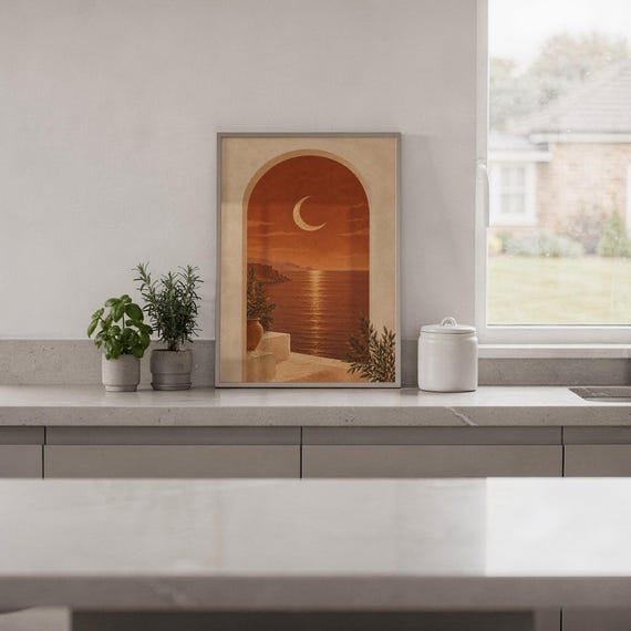 Mediterranean crescent moon arch print standing on a white kitchen counter beside potted herbs.
