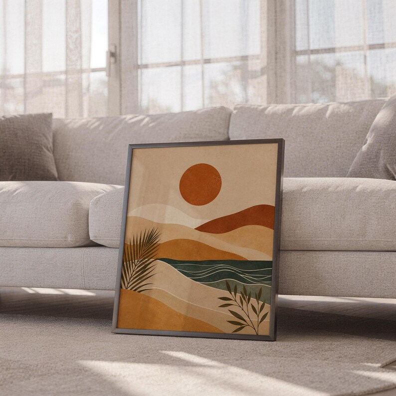 Boho terracotta sun and waves art print framed leaning against floor sofa in cozy living room decor.