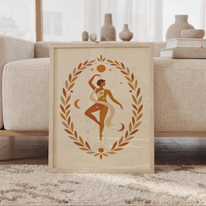 Terracotta dancing goddess wall art print in a wood frame leaning against a cream sofa in a bright modern living room.