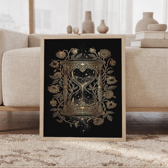 Gothic hourglass wall art print featuring intricate gold skulls, blooming and wilted roses, celestial stars, and an ornate Victorian-inspired hourglass on a deep black background, framed and leaning against a beige sofa on a textured rug in a bright Scandinavian living room.
