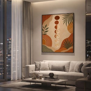 Boho moon phases art print showing a vertical row of moon phases with abstract organic shapes and palm leaves in terracotta, sage green and beige, hanging above a light gray sofa in a modern living room with evening city views through tall windows.