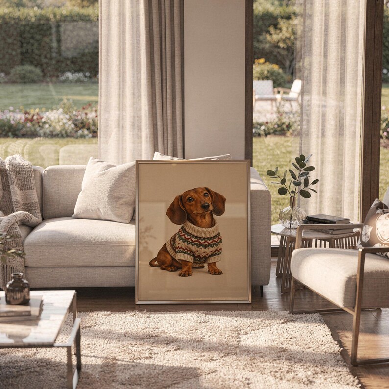 Dachshund sweater wall art print in a silver frame leaning against a sofa beside a decorative marble sphere.
