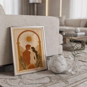 Framed terracotta arch art print leaning on a patterned rug next to a white armchair and decorative stone sphere.