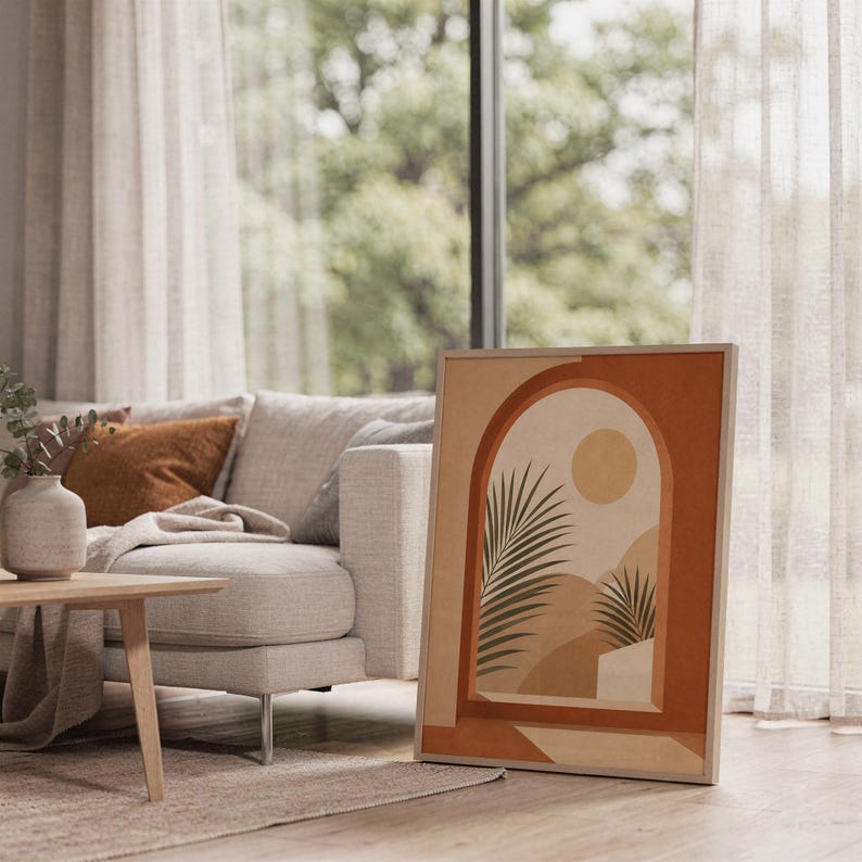 Terracotta arch palm poster framed on bright sunlit living room floor next to window.