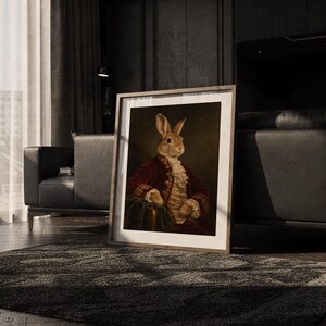 Regal rabbit portrait wall art print leaning on the floor beside a cream armchair next to large garden windows.