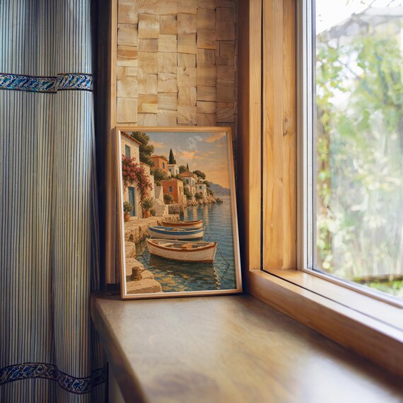 Mediterranean coastal village wall art print standing on a wooden window sill in warm natural light.