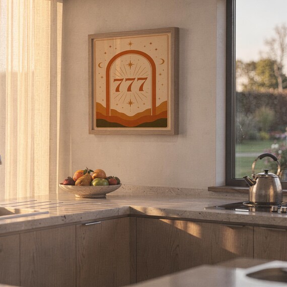 Framed celestial 777 lucky number wall art hanging on a sunny kitchen wall next to a clean countertop and fruit bowl.
