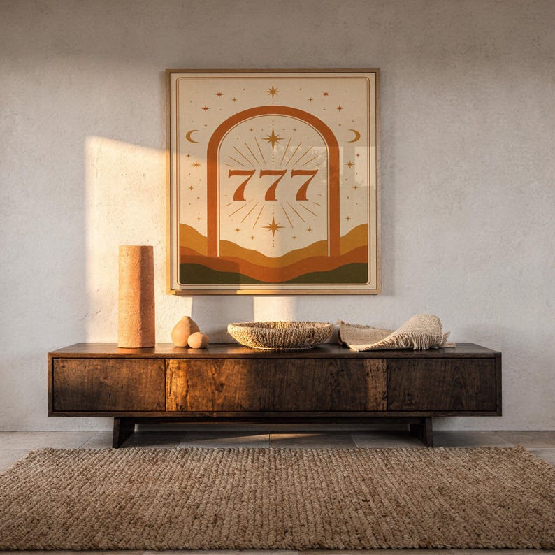 Aesthetic 777 angel number framed print styled on a rustic wooden credenza in warm golden hour sunset light.