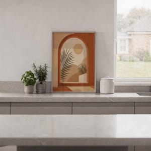 Minimalist terracotta arch print framed on white kitchen counter against clean wall decor.