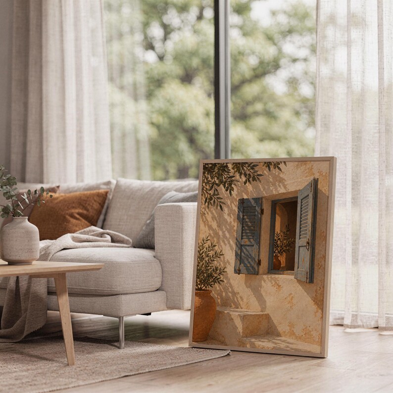 Mediterranean blue shutter wall art print leaning on the floor beside a cream armchair next to large garden windows.