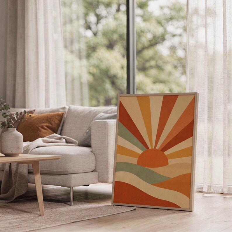 Retro geometric sunrise print leaning on the floor beside a cream armchair next to large garden windows.