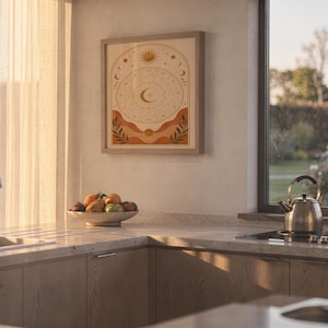 Zodiac wheel wall art print hanging above a stone countertop with a fruit bowl in a sunny kitchen.