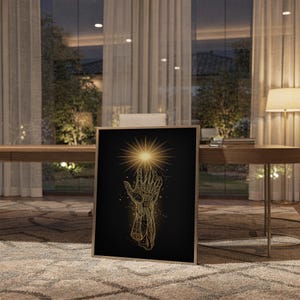 Celestial hand wall art print standing on a wooden desk in a home office in warm evening light.