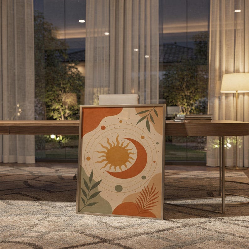 Celestial sun and moon art print standing on a wooden desk in a home office in warm evening light.