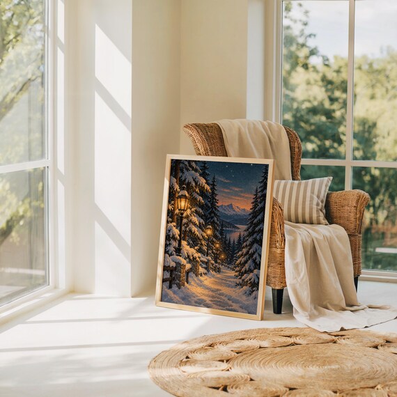 Snowy forest path wall art print leaning on the floor beside a rattan armchair and jute rug in a bright sunlit room.
