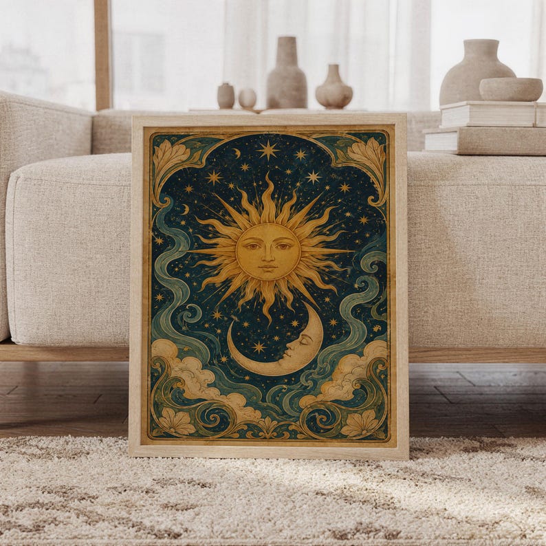 Celestial sun and moon wall art print featuring antique gold sun rays, a crescent moon, twinkling stars, deep navy blue skies, teal swirling clouds, and ornate botanical borders in a vintage celestial style, framed and leaning against a beige sofa on a textured rug in a bright Scandinavian living room.