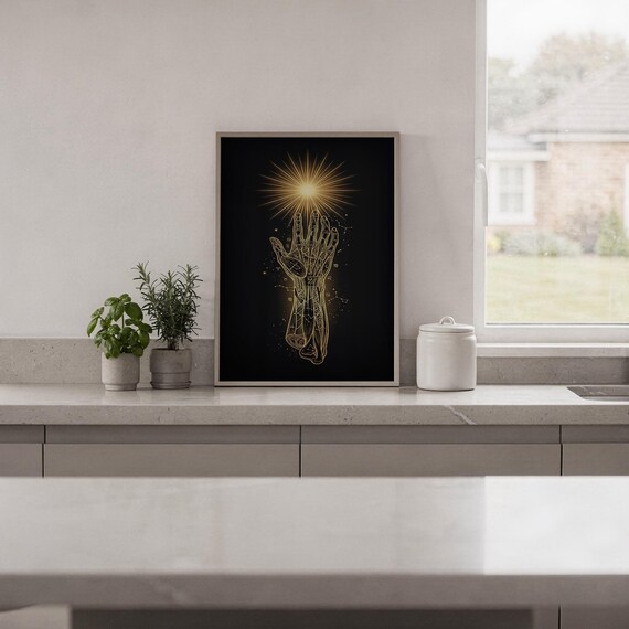 Celestial hand wall art print standing on a white kitchen counter beside potted herbs.